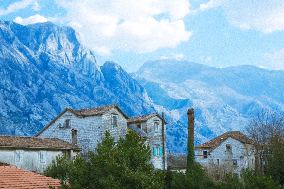 Charming village houses set against a stunning mountain landscape under a bright sky.