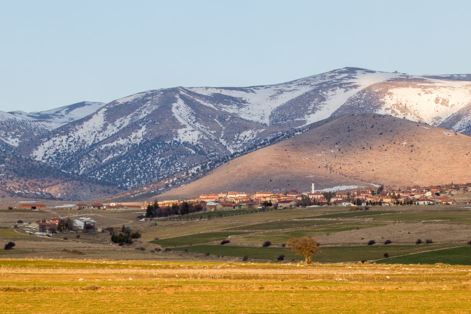 Charming rural mountain village with snowcapped peaks in a serene landscape at day.